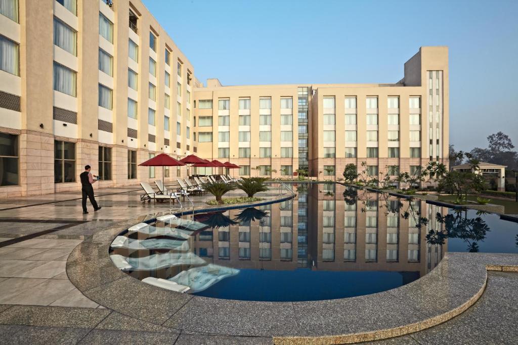 a man walking in front of a building with a pool at Radisson Blu Hotel Rudrapur in Rudrapur