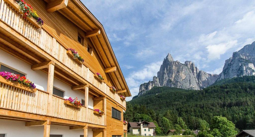 a building with flowers on it with mountains in the background at Haus Bernard in Siusi