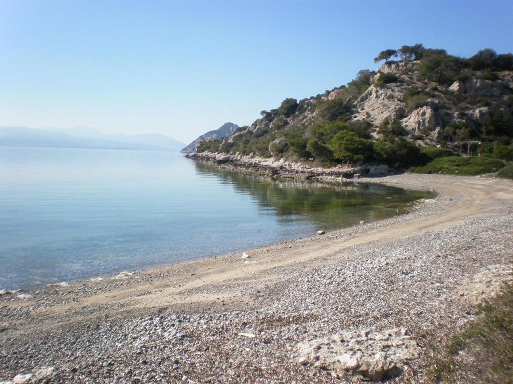 a beach with a rocky shoreline and the water at Marvelous house by the sea in Vouliagmeni Lake