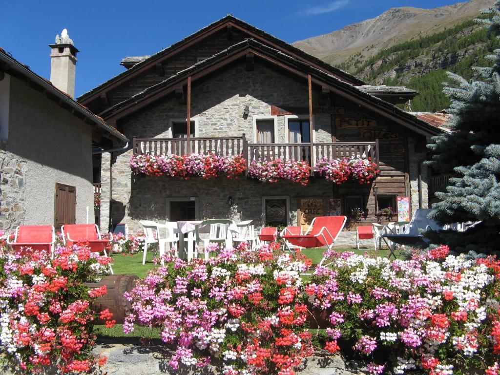 a house with a balcony with red chairs and flowers at Hotel Petit Giles in Cogne