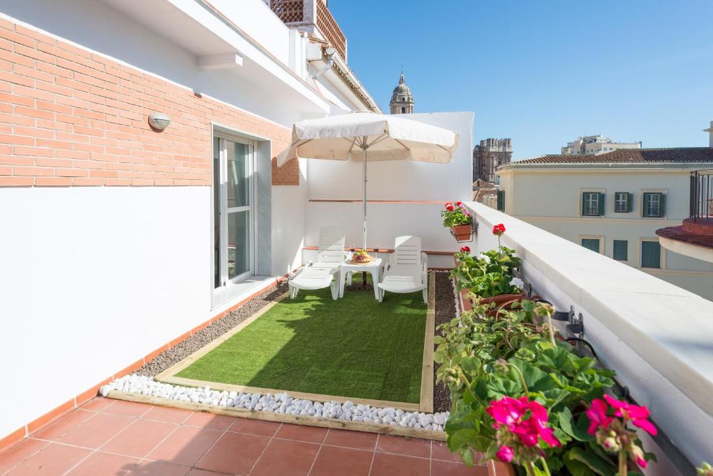 patio con mesa y sombrilla en el balcón en Ahro Suites, en Málaga