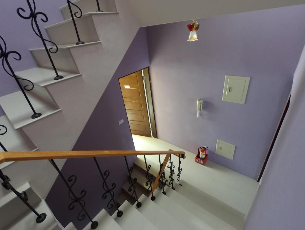 a staircase with purple walls and a wooden railing at Eik Forest B&amp;B in Taitung City