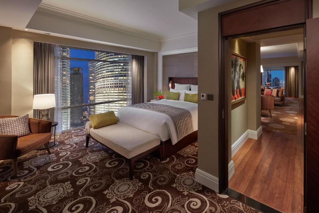 A king bedroom with a chaise, city-facing window and a mirrored view into the adjoining room.