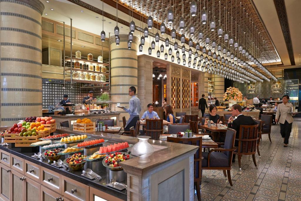 A bustling restaurant dining room with an extensive fruit and dessert buffet.