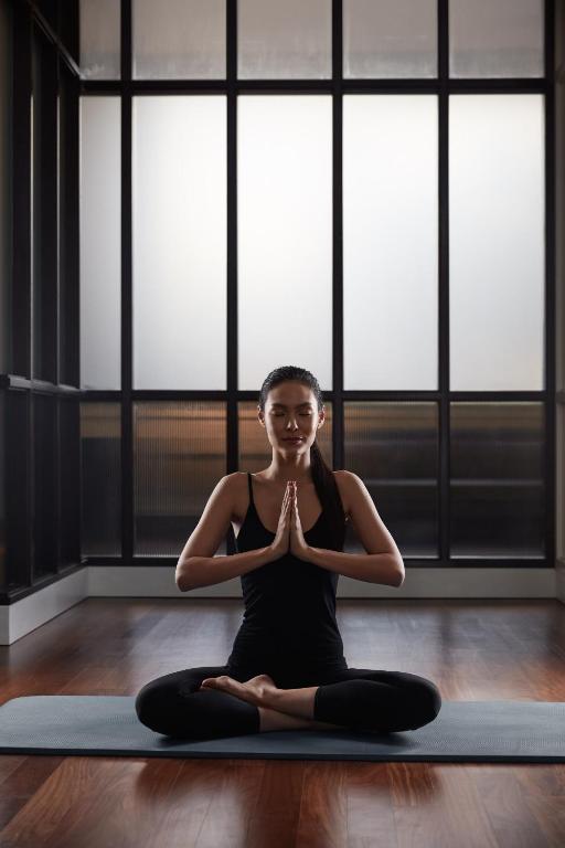 A bright studio where a guest is practising yoga on a mat.