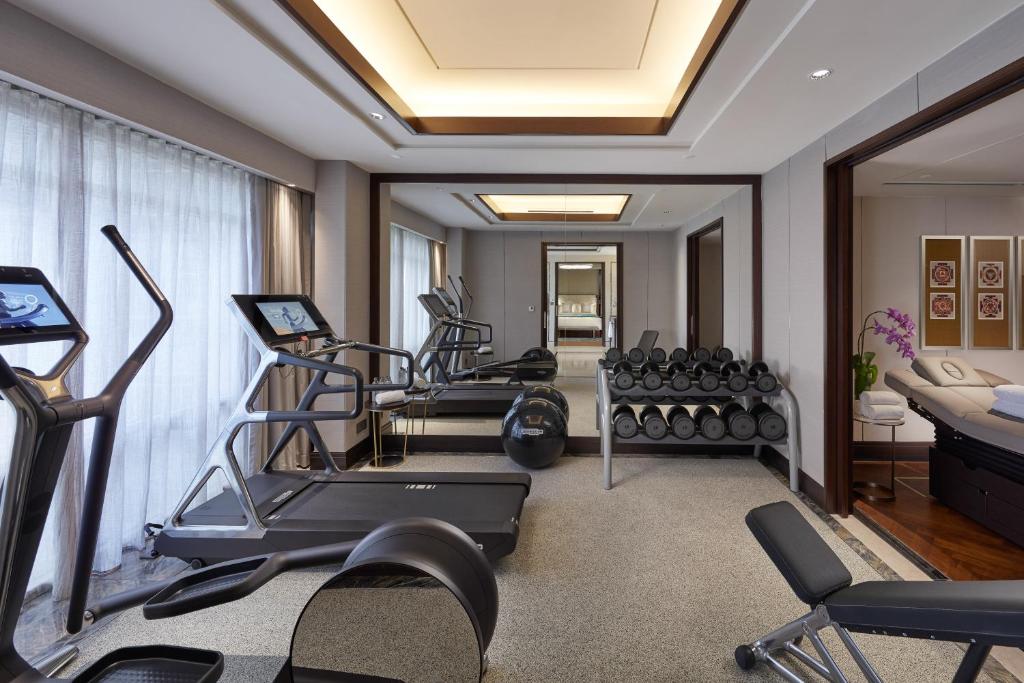 A bright hotel fitness room with cardio equipment, free weights and a mirrored wall.