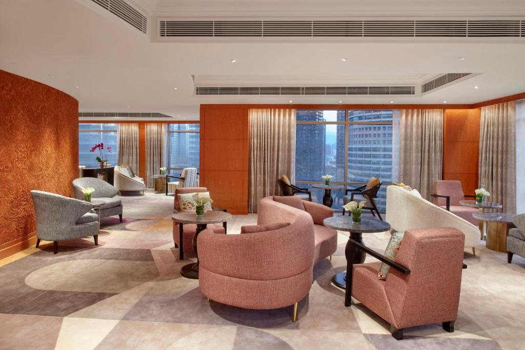A bright lobby lounge with clusters of upholstered chairs, tables and large windows.