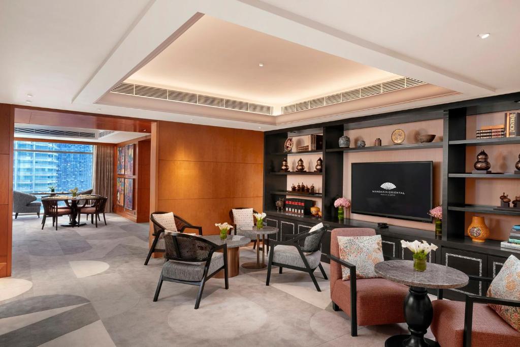 A polished lounge with armchairs, side tables, shelving and a television.