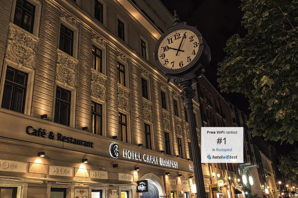 a clock on a pole in front of a building at Carat Boutique Hotel in Budapest
