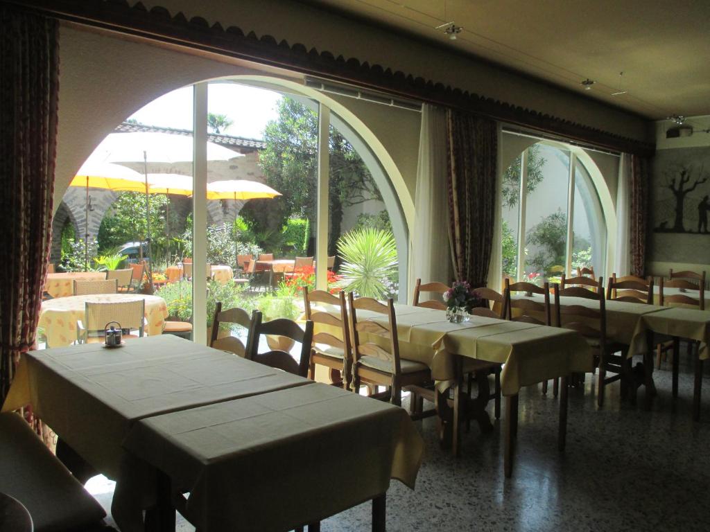 a dining room with tables and chairs and large windows at Hotel Arcadia in Ascona
