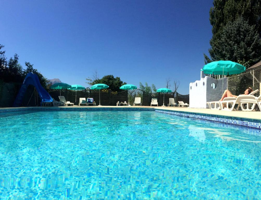 une grande piscine avec un toboggan et des parasols dans l'établissement Camping Les Grillons, à Embrun