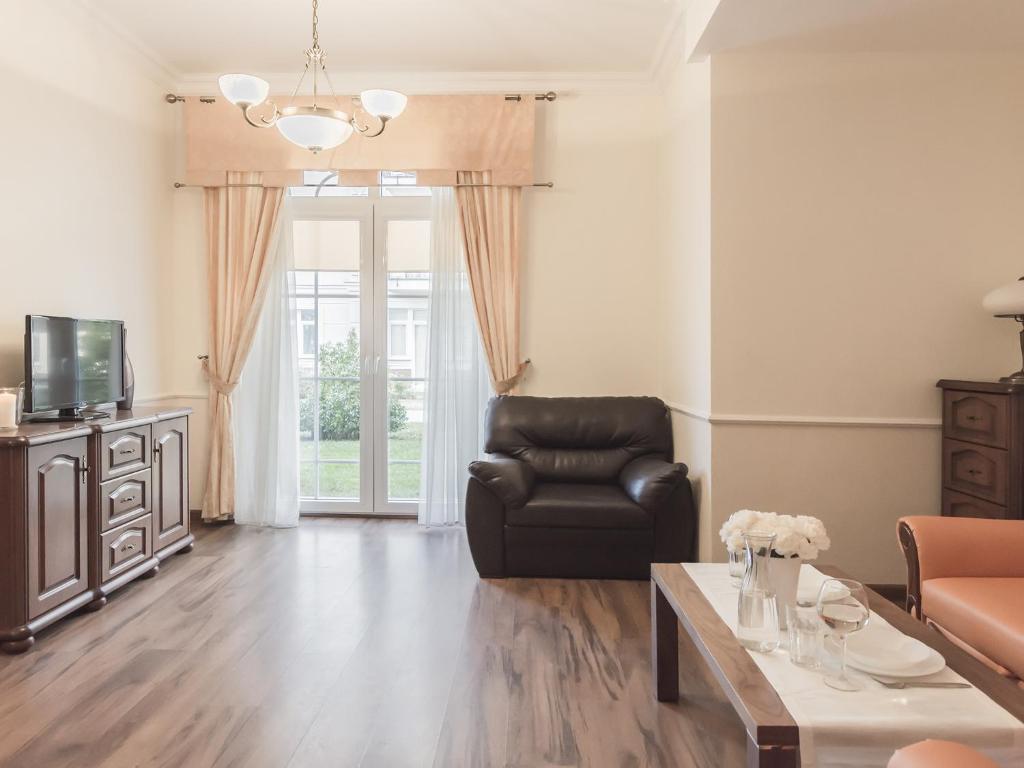 a living room with a leather chair and a television at VacationClub - Trzy Korony Wazow Apartment 12 in Świnoujście