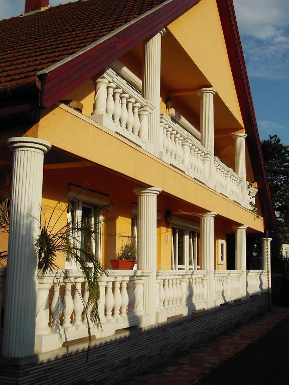 un edificio amarillo con columnas blancas y balcón en Koppi Ház, en Siófok