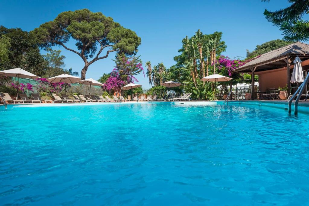 ein Schwimmbad mit blauem Wasser und Sonnenschirmen in der Unterkunft Rock Hotel in Gibraltar