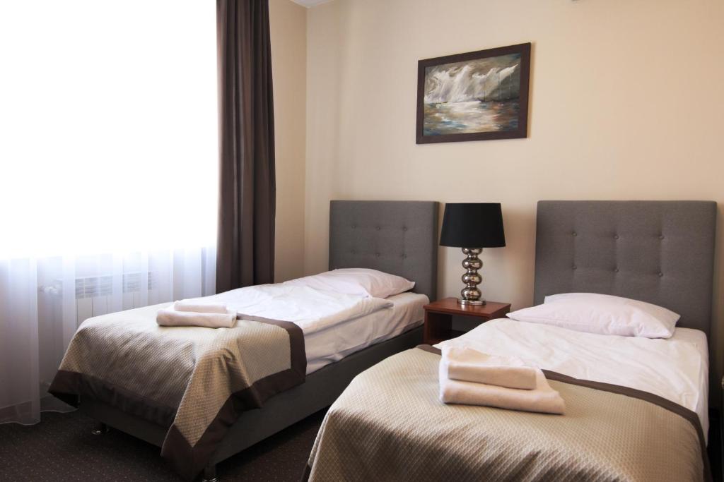 two beds in a hotel room with a window at Centrum Konferencyjno-Apartamentowe Mrówka in Warsaw