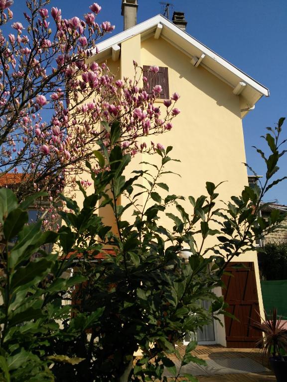 une maison avec un arbre en fleurs devant dans l'établissement Atelier Liberation, à Bourgoin-Jallieu