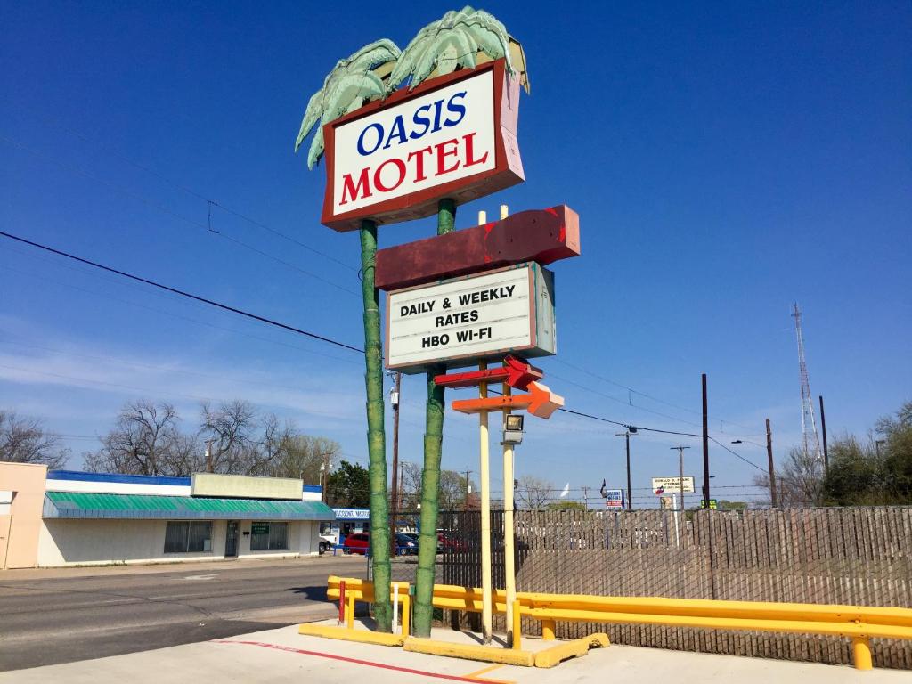 a sign for anolis motel on the side of a street at Oasis Motel in Arlington