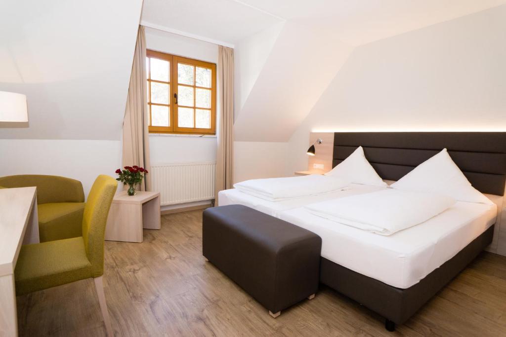 um quarto de hotel com uma cama e uma cadeira em Hotel-Restaurant Bibermühle GmbH em Tengen