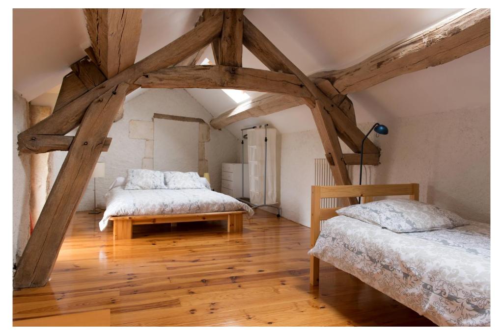 2 łóżka w pokoju z drewnianymi belkami stropowymi w obiekcie Domaine de la Grange aux Dîmes w mieście Feux