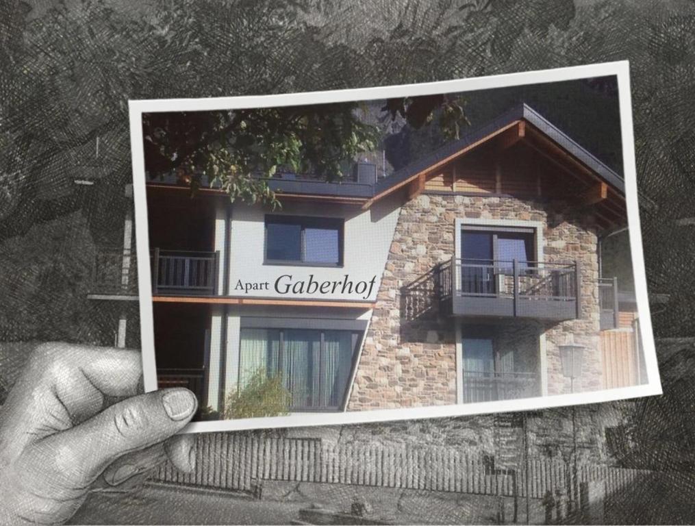 a person holding up a picture of a building at Apart Gaberhof in Tarrenz