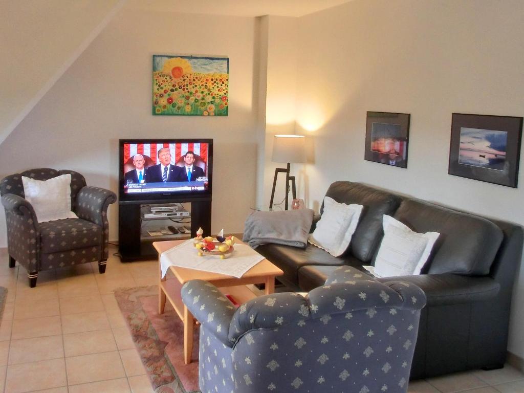 Sala de estar con 2 sofás de cuero y TV en Villa Hermes en Hagen