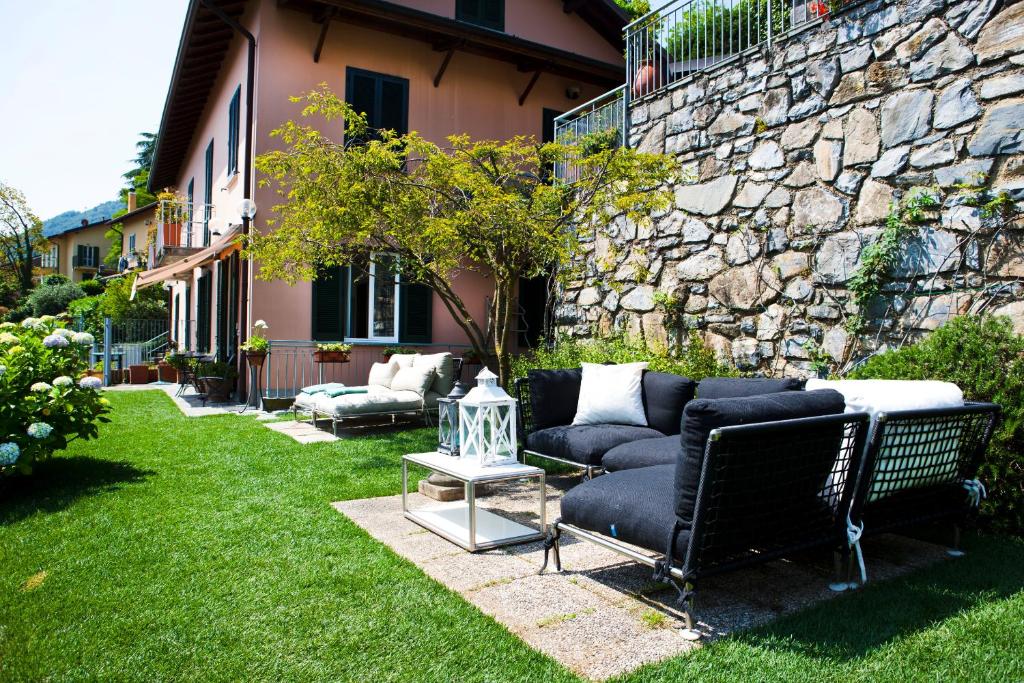 a couch sitting in a yard next to a stone wall at Belvedere Holiday Home in Bellagio