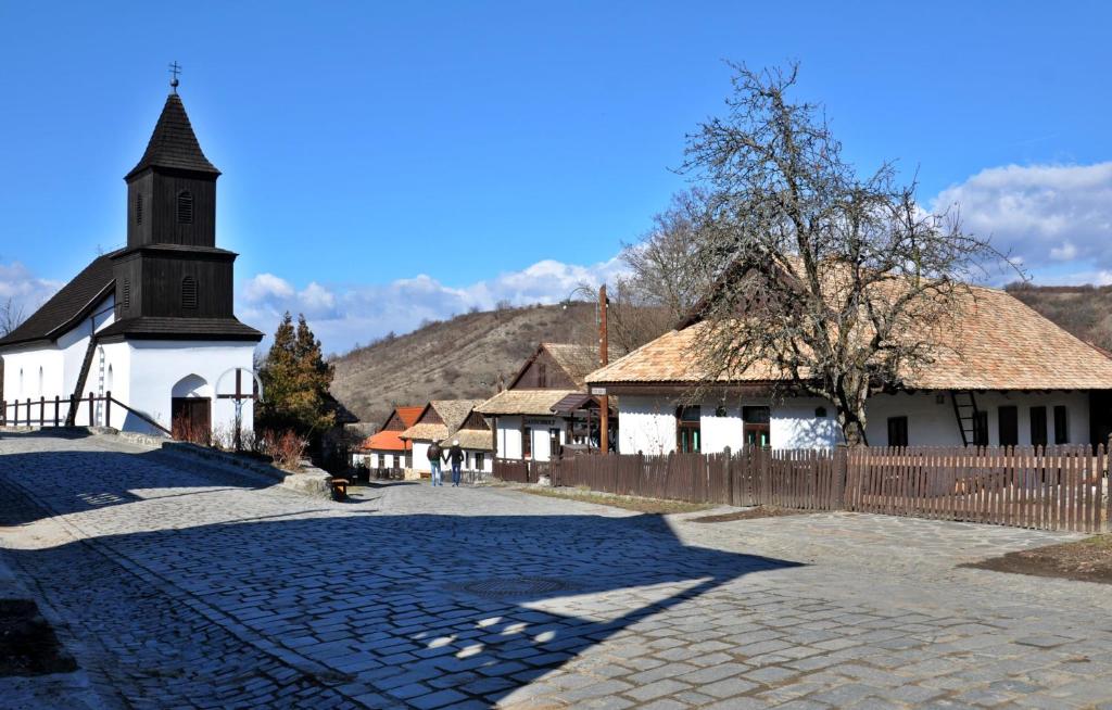 eine kleine Kirche mit einem Zaun und einer Kopfsteinpflasterstraße in der Unterkunft Nefelejcs Vendégház Hollókő in Hollókő