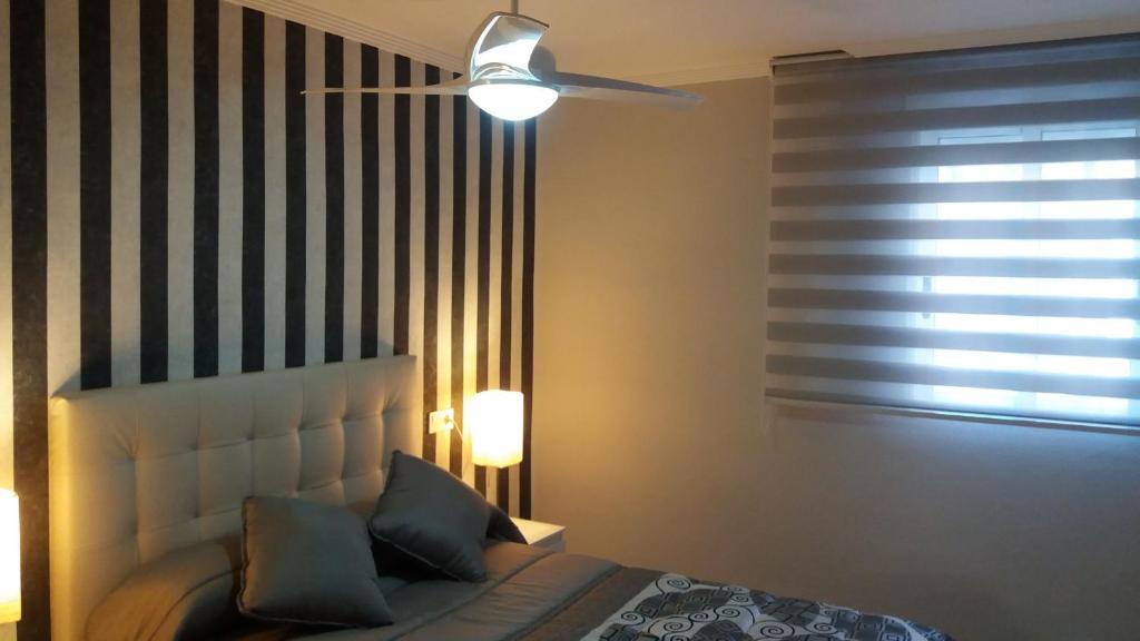 een slaapkamer met een bed en een plafondventilator bij APARTMENTSUITESPAIN Beach Economy in Valencia