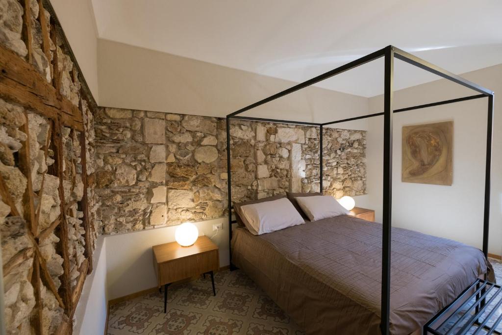 een slaapkamer met een bed en een stenen muur bij Il Fuoco di Archimede - Ortigia in Siracusa