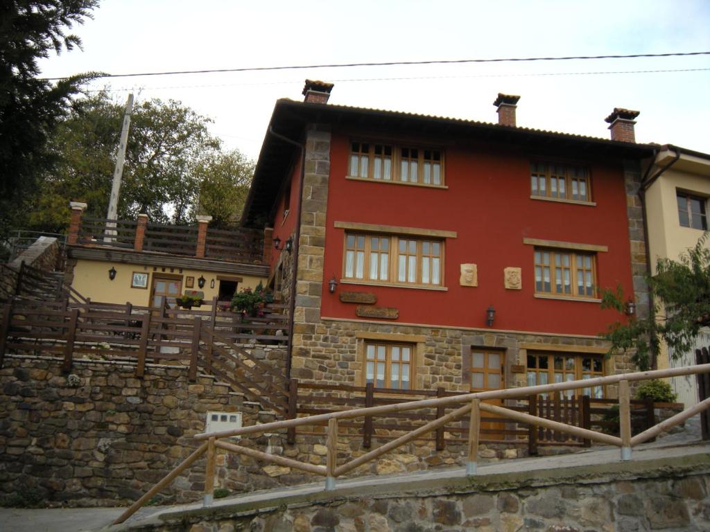 una vieja casa roja con una pared de piedra en La Portiella, en Bueres