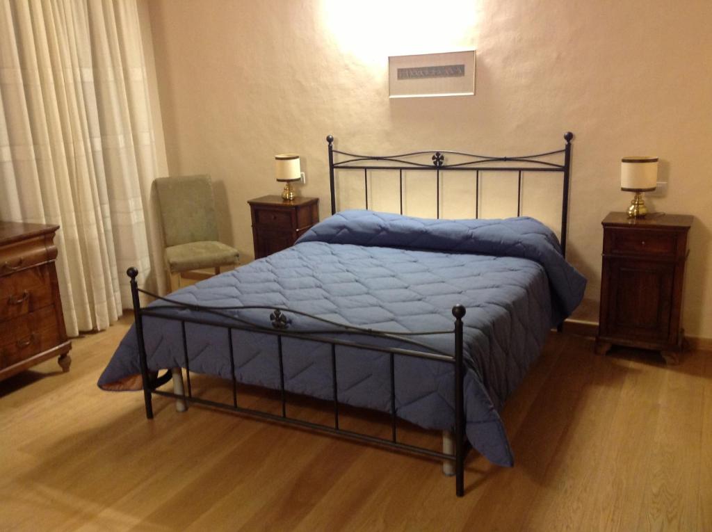 a bedroom with a bed with a blue comforter at San Francesco Bedrooms in Urbino