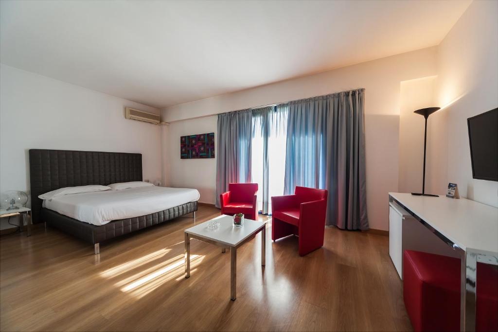 ein Hotelzimmer mit einem Bett und roten Stühlen in der Unterkunft Park Hotel Residence in Crema