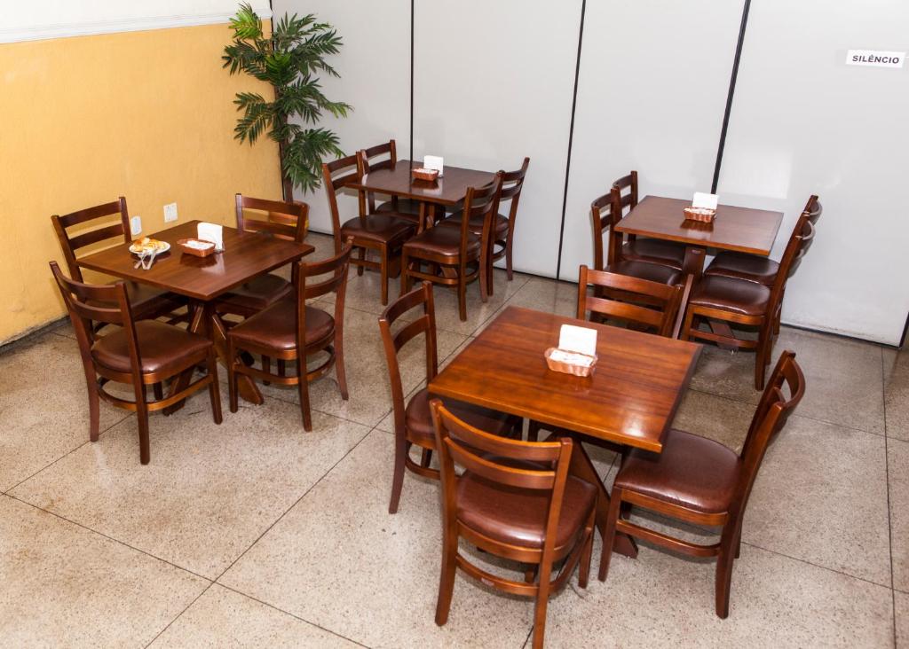 a dining room with wooden tables and chairs at Hotel Oasis in Contagem