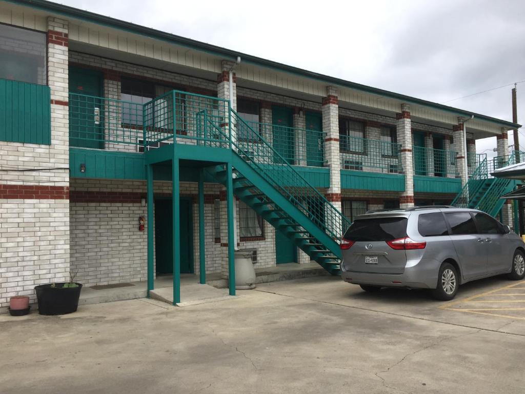 un coche aparcado frente a un edificio con una escalera en Garden Inn Motel en San Antonio