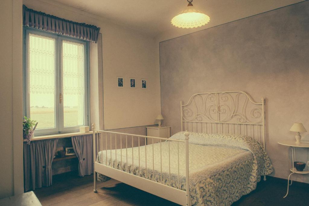 a bedroom with a white bed and a window at La Vigna Del Maestro in Bene Vagienna