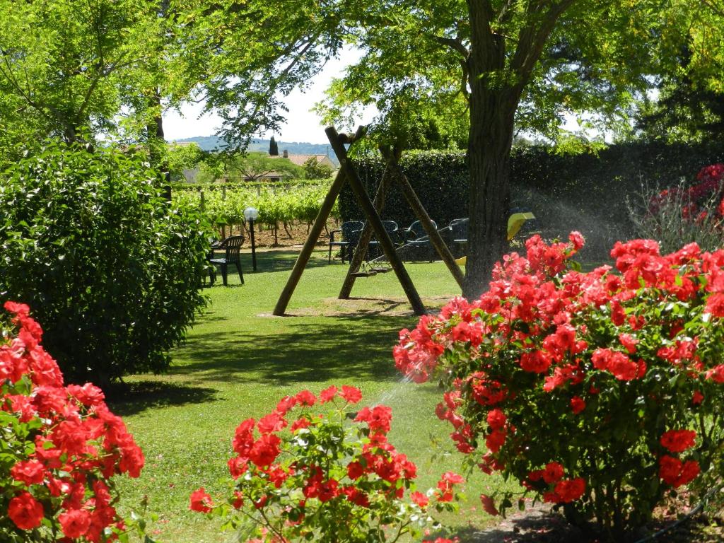 マリアーノ・イン・トスカーナにあるAgriturismo Fusiniの赤い花とブランコのある庭園