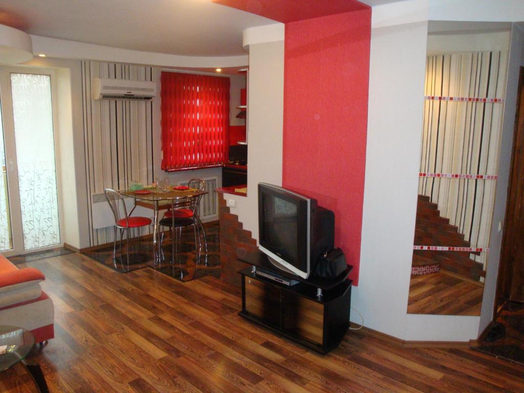 ヘルソンにあるMaxim Apartmentのリビングルーム(テレビ、テーブル、椅子付)