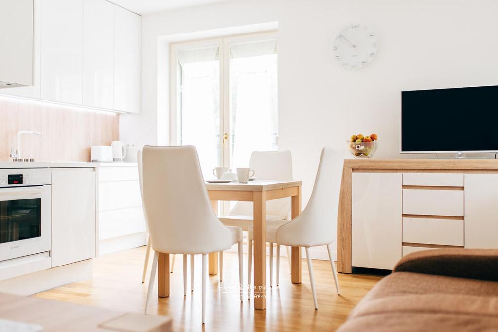a white kitchen with a table and white chairs at Apartament 3 - Bliżej Zdroju in Polanica-Zdrój