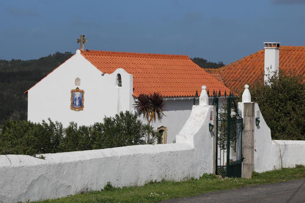 a white house with a fence and a church at Casa da Quinta do Outeiro in Reveles