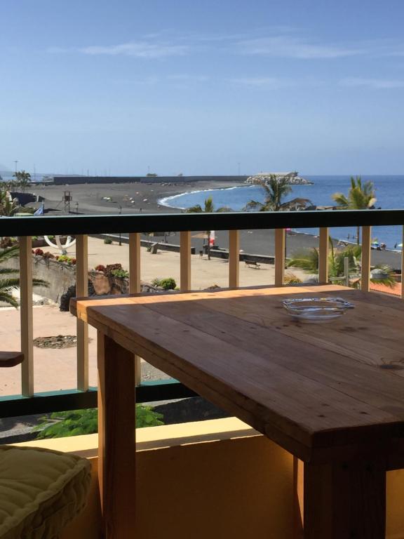 a wooden table on a balcony with a view of the beach at Apartamento Danmi y Janet in Tazacorte