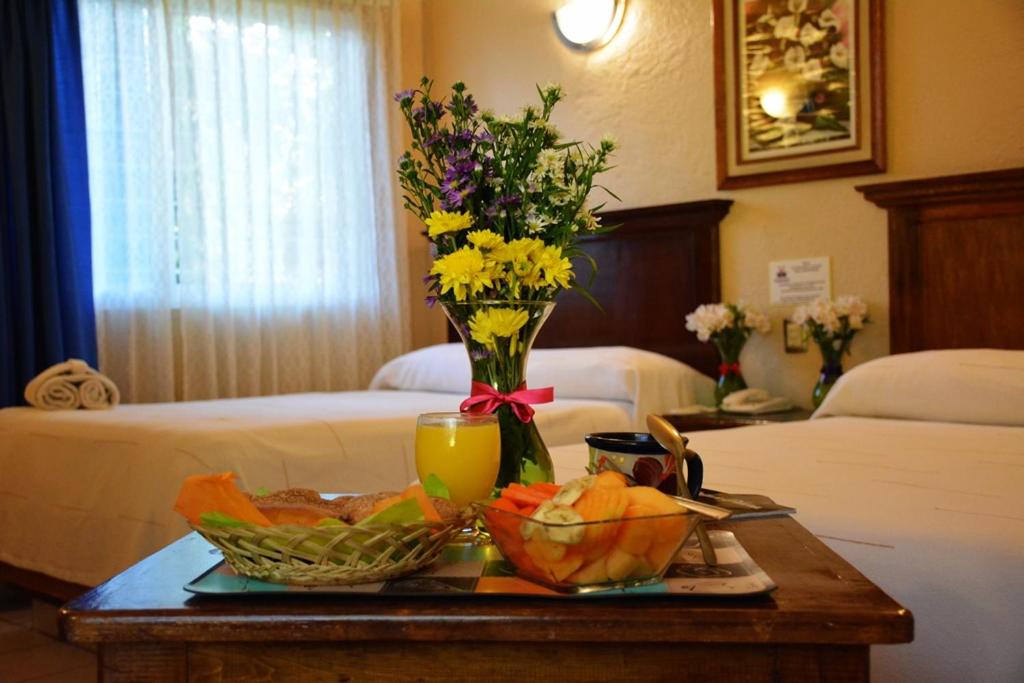 einen Tisch mit einem Tablett mit Obst und einer Vase mit Blumen in der Unterkunft Hotel La Hacienda in Tuxtla Gutiérrez
