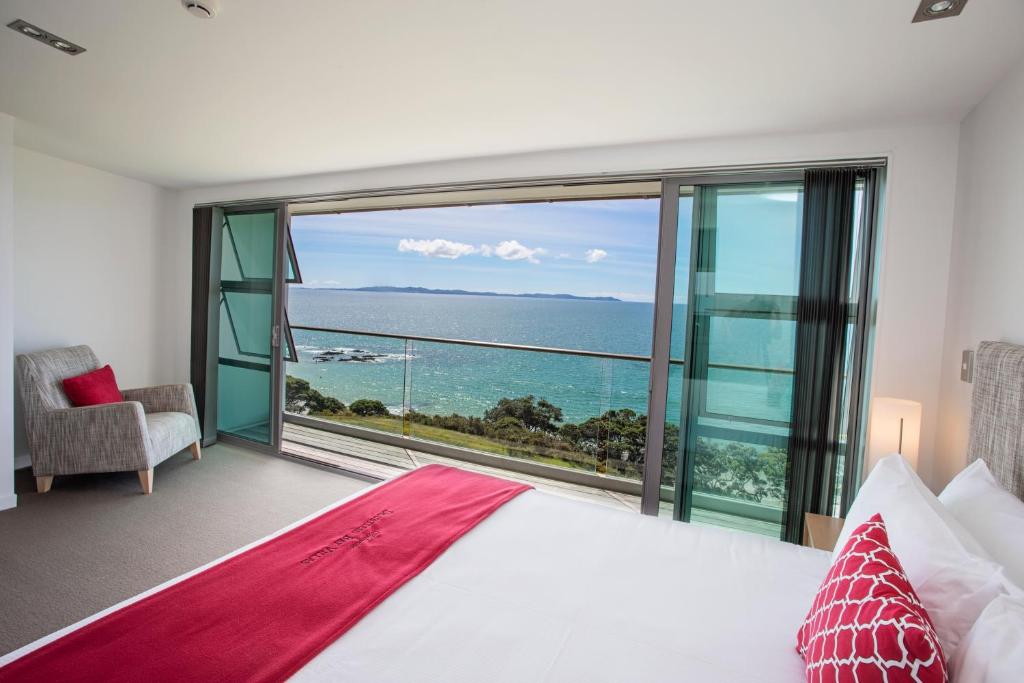 a bedroom with a large bed and a view of the ocean at Doubtless Bay Villas in Cable Bay