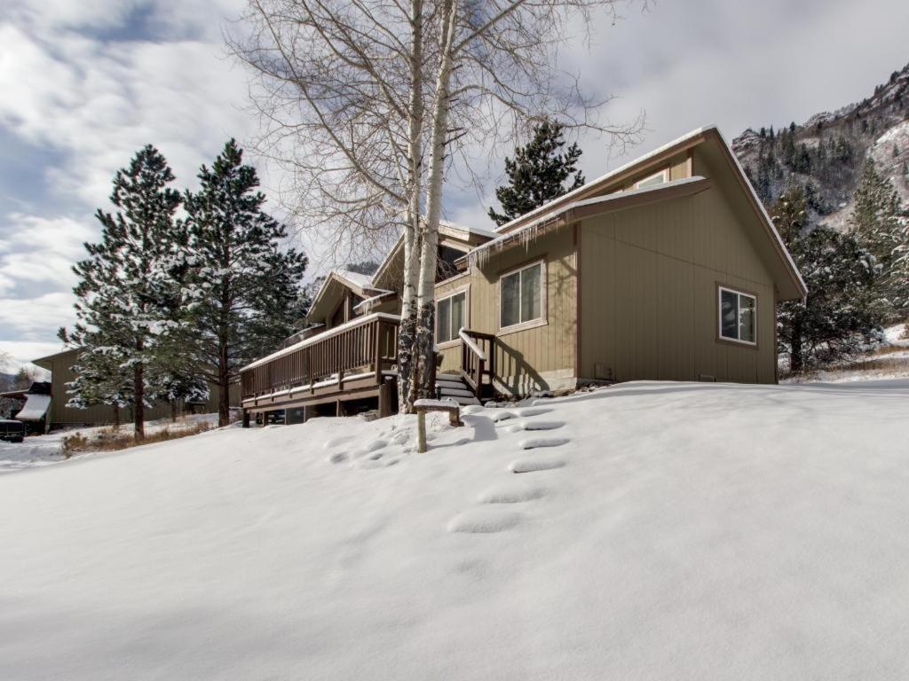 una casa con huellas en la nieve delante de ella en The Cabins at Filoha Meadows en Redstone