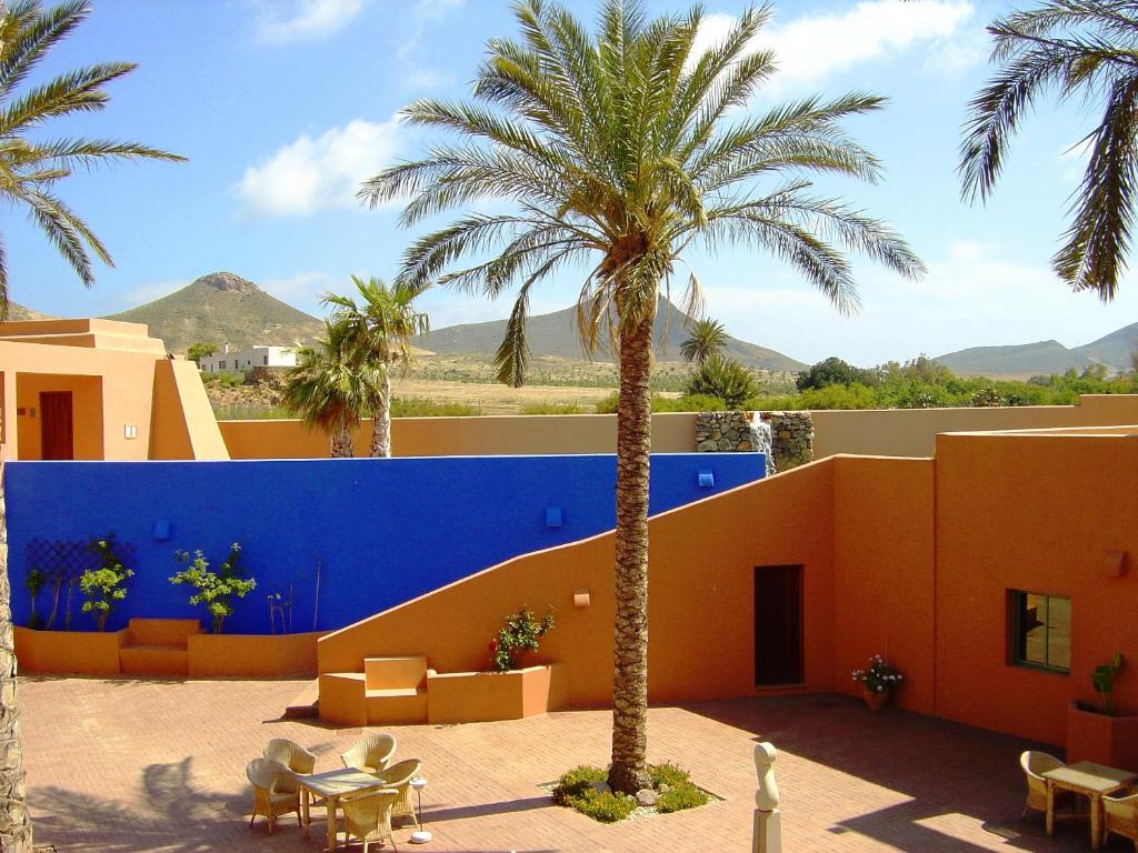 a building with a palm tree in front of it at Hotel de Naturaleza Rodalquilar & Spa Cabo de Gata in Rodalquilar