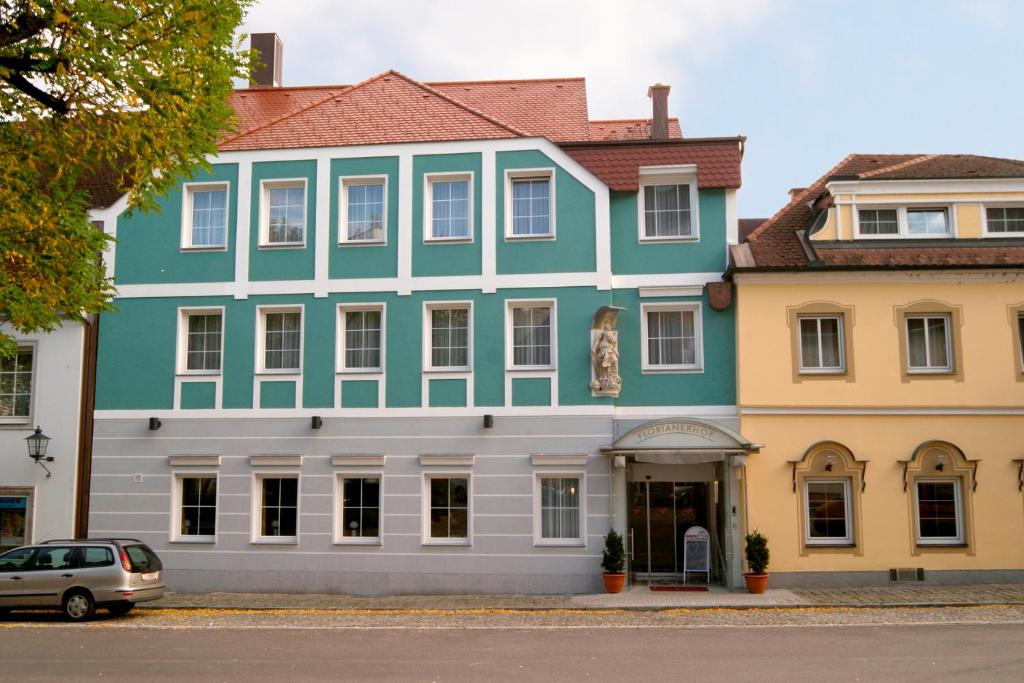 un grande edificio bianco e blu con un'auto parcheggiata di fronte di Hotel Florianerhof a Markt Sankt Florian