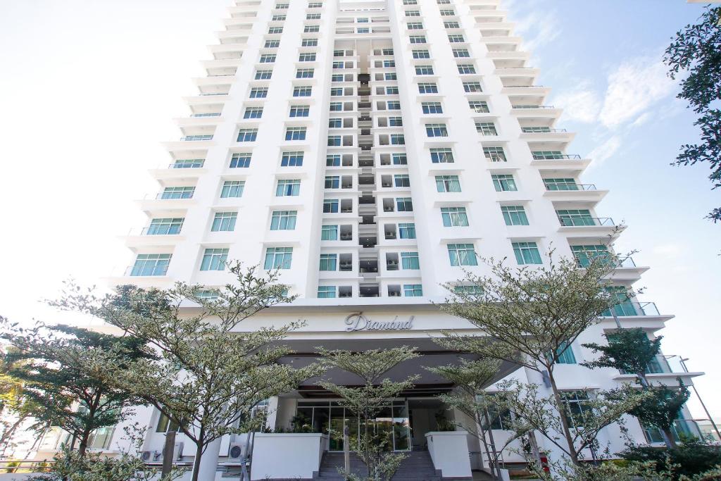 ein hohes weißes Gebäude mit Bäumen davor in der Unterkunft Imperial Suites Miri , Diamond Tower in Miri