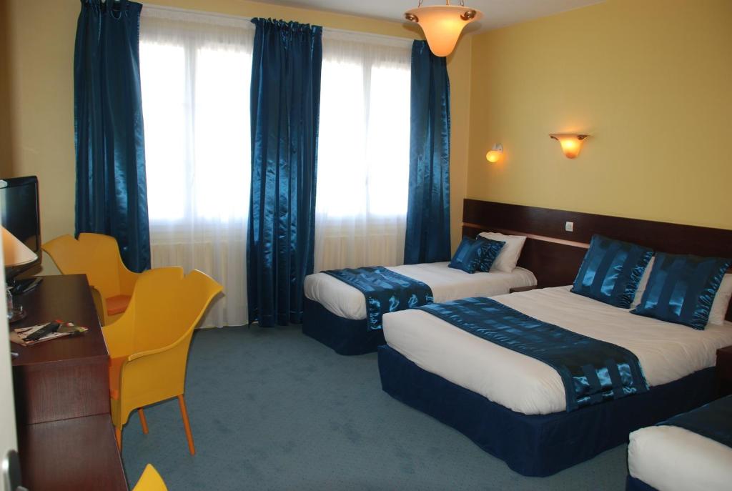 een hotelkamer met 2 bedden en een bureau bij The Originals City, Hôtel Cathédrale, Lisieux (Inter-Hotel) in Lisieux