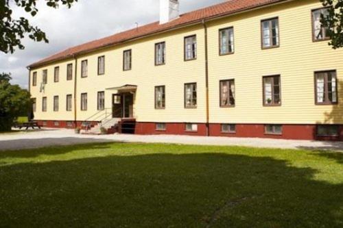 a large yellow building with a grass field in front of it at Brukshotellet Roma B&B in Romakloster