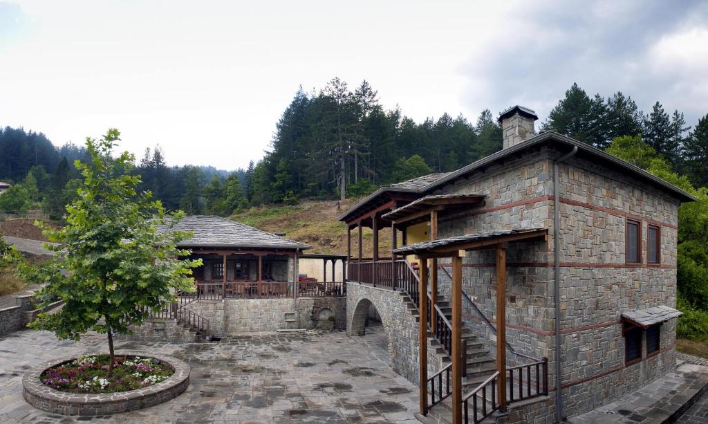 un gran edificio de piedra con un árbol en un patio en Kerasies Guesthouse, en Vovoúsa