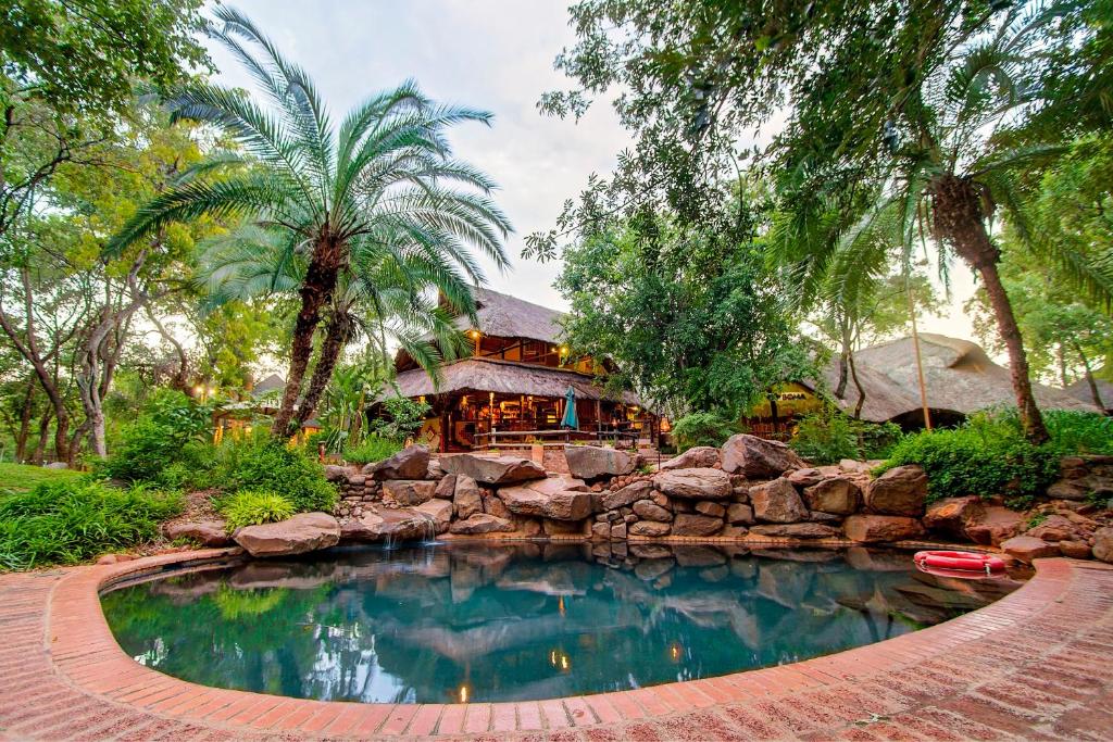a swimming pool in front of a house with a resort at Lokuthula Lodge in Victoria Falls